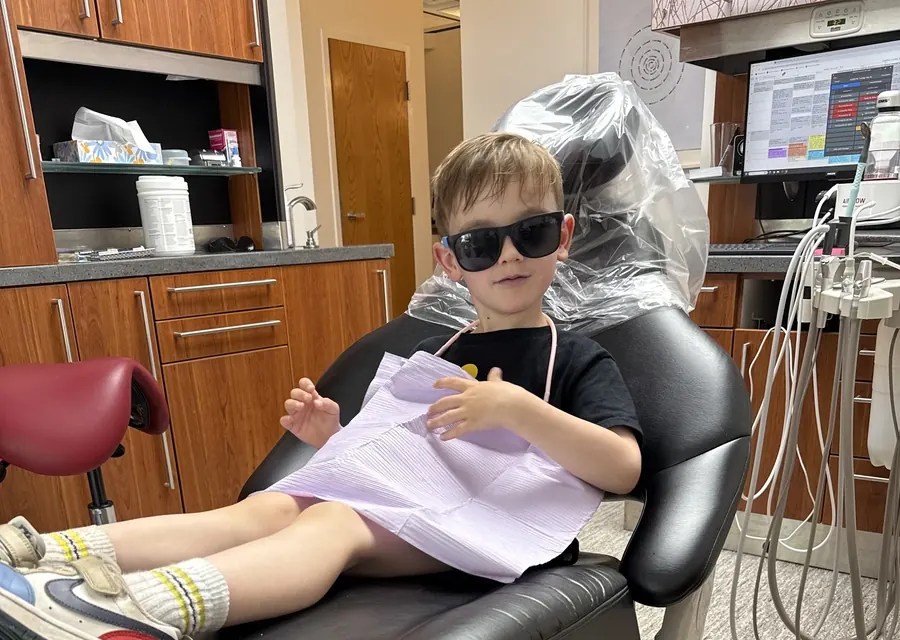 A young patient in sunglasses, relaxed in a treatment chair at Falmouth Dental Health.
